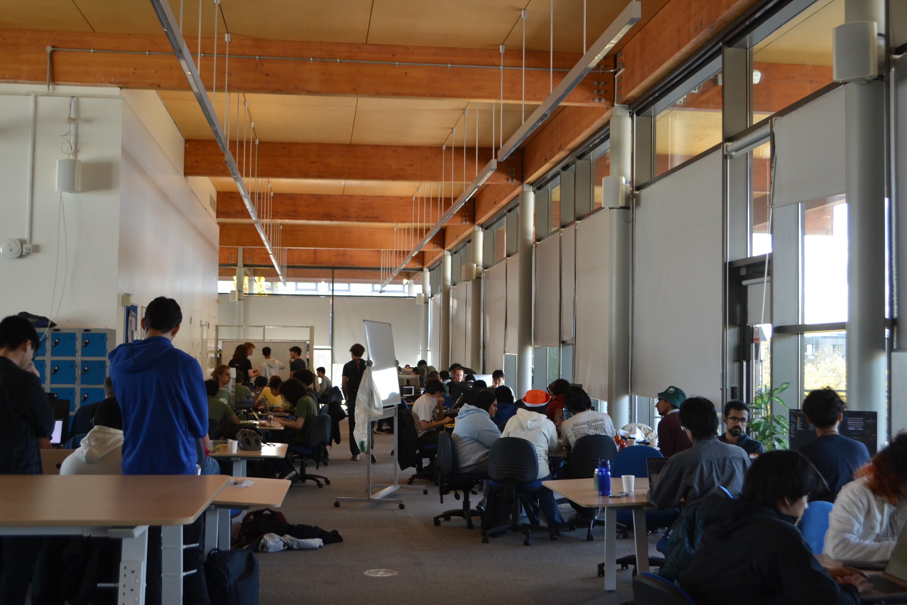 Wide shot of the Intel Lab filled with students working at tables during CamHack 2025
